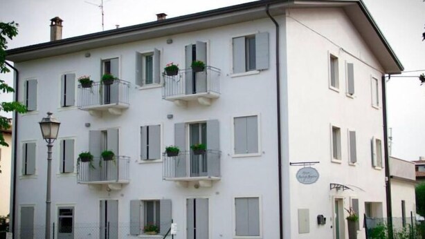 Un immeuble à plusieurs étages doté de balcons, dont certains sont ornés de plantes en pot.