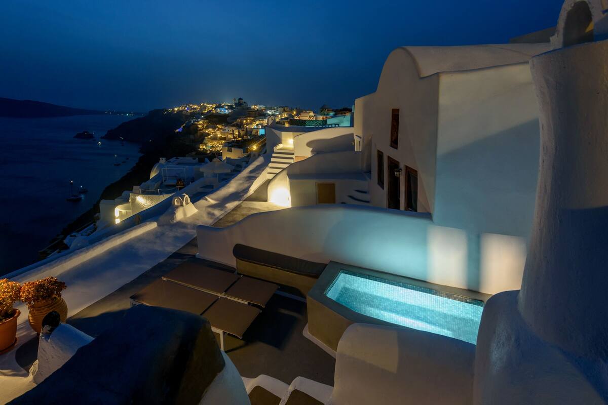 Un hotel moderno con piscina, arquitectura blanca y vista al mar de noche.