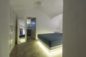 Un dormitorio con cama, armario y baño visible a través de una puerta abierta.
