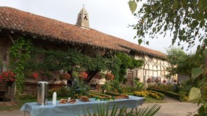 Edifici rústic amb teulada de teules i parets cobertes d'ivarnades.