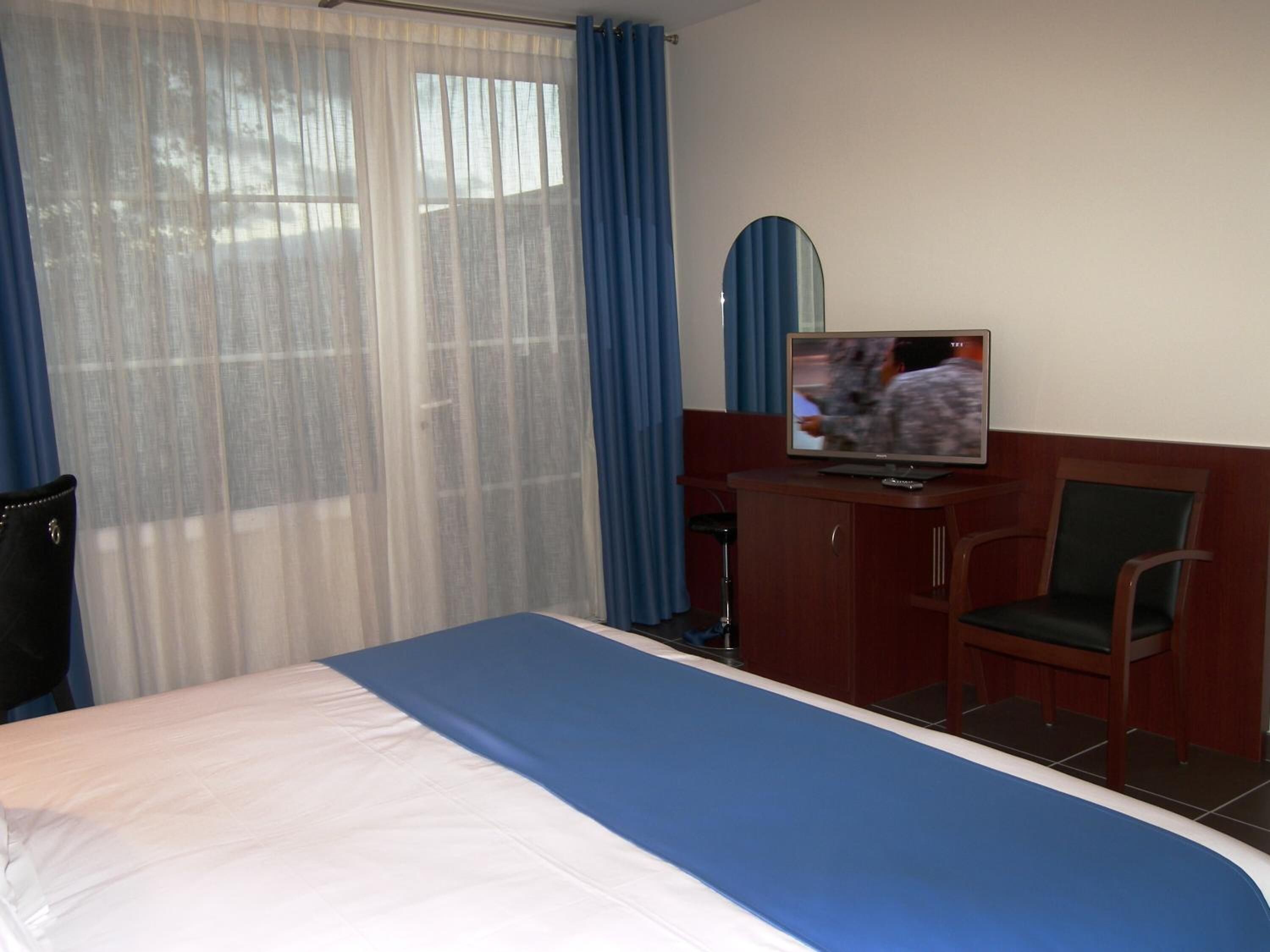 Una habitación de hotel con cama, televisión, escritorio y silla.