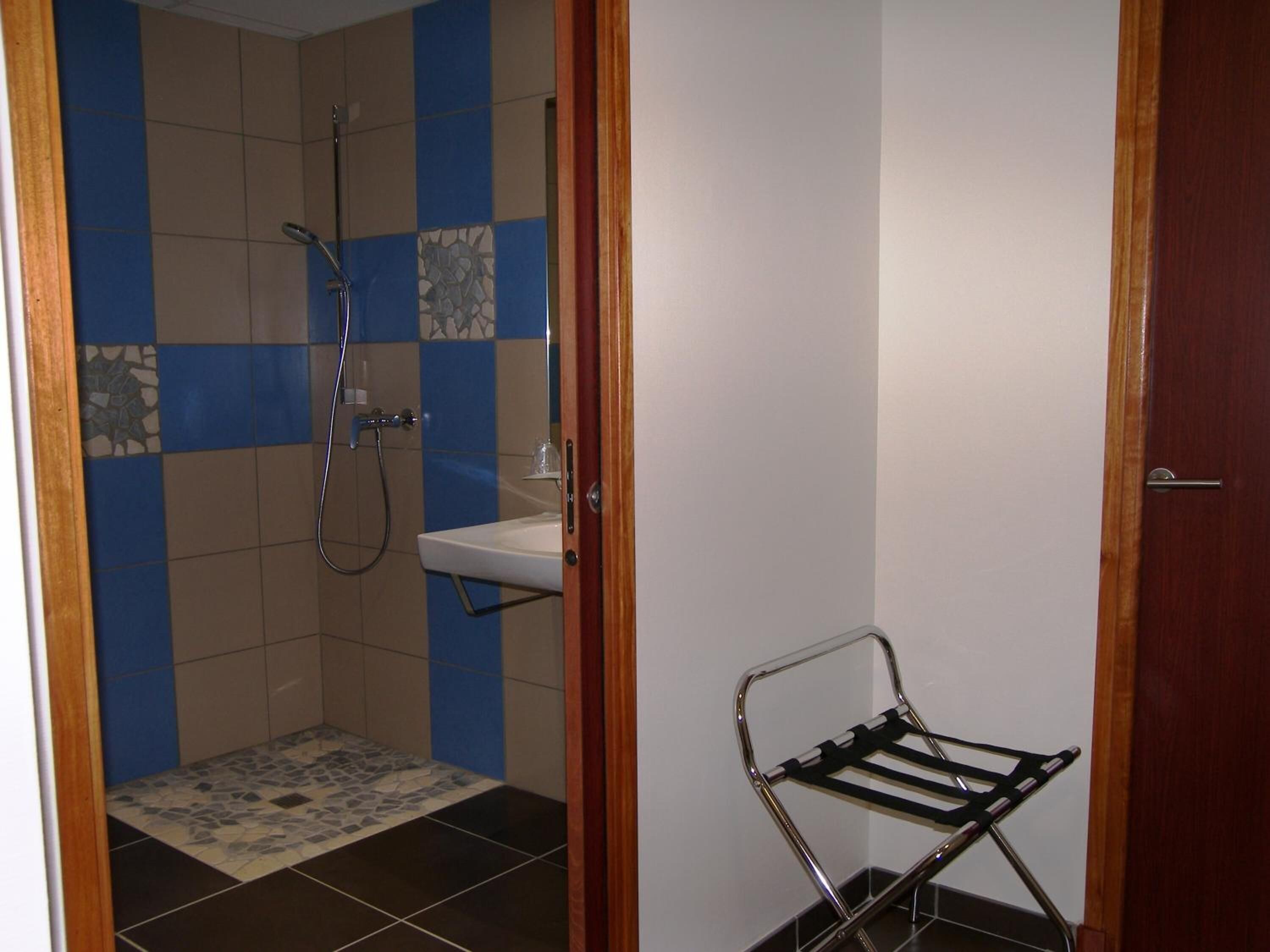 Une salle de bain avec une douche, un lavabo et un porte-serviettes.