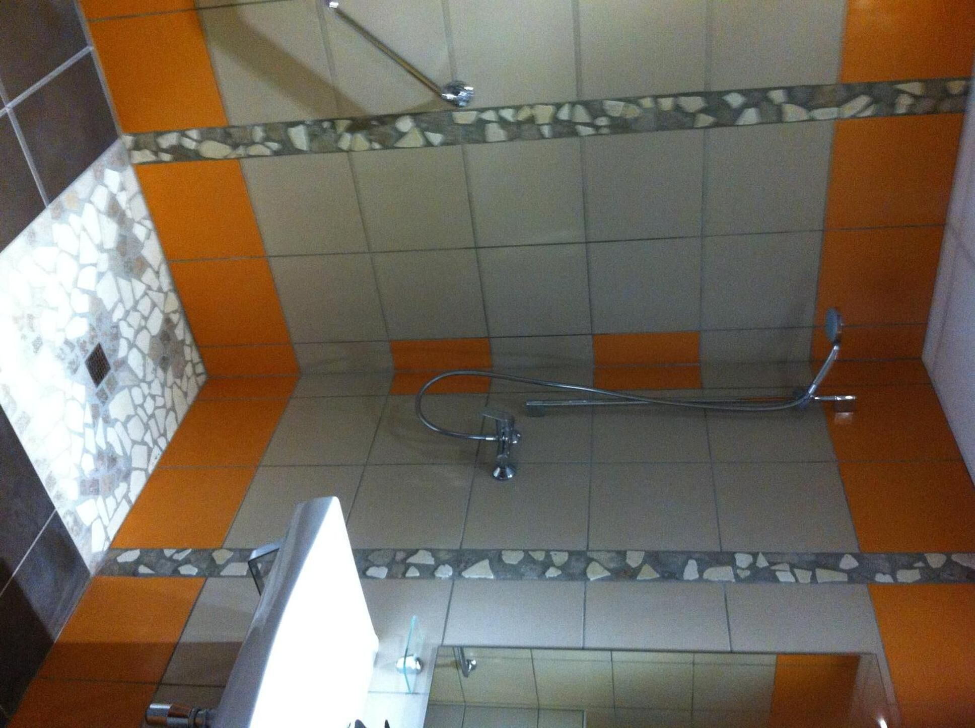 Ein Badezimmer mit Dusche, gefliesten Wänden und einer Zierleiste.