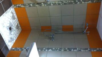 Ein Badezimmer mit Dusche, gefliesten Wänden und einer Zierleiste.