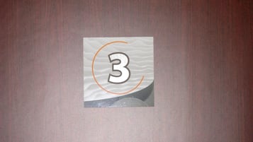 Un adhesivo con el número 3 sobre una superficie de madera.