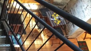 A wooden staircase with a metal railing leading to a room with a wooden floor and a window. - Marco's Heuboden (Oberzissen)