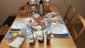 A breakfast setting with a table set for two, including plates, cutlery, a bread basket, a coffee pot, and various condiments. - Marco's Heuboden (Oberzissen)