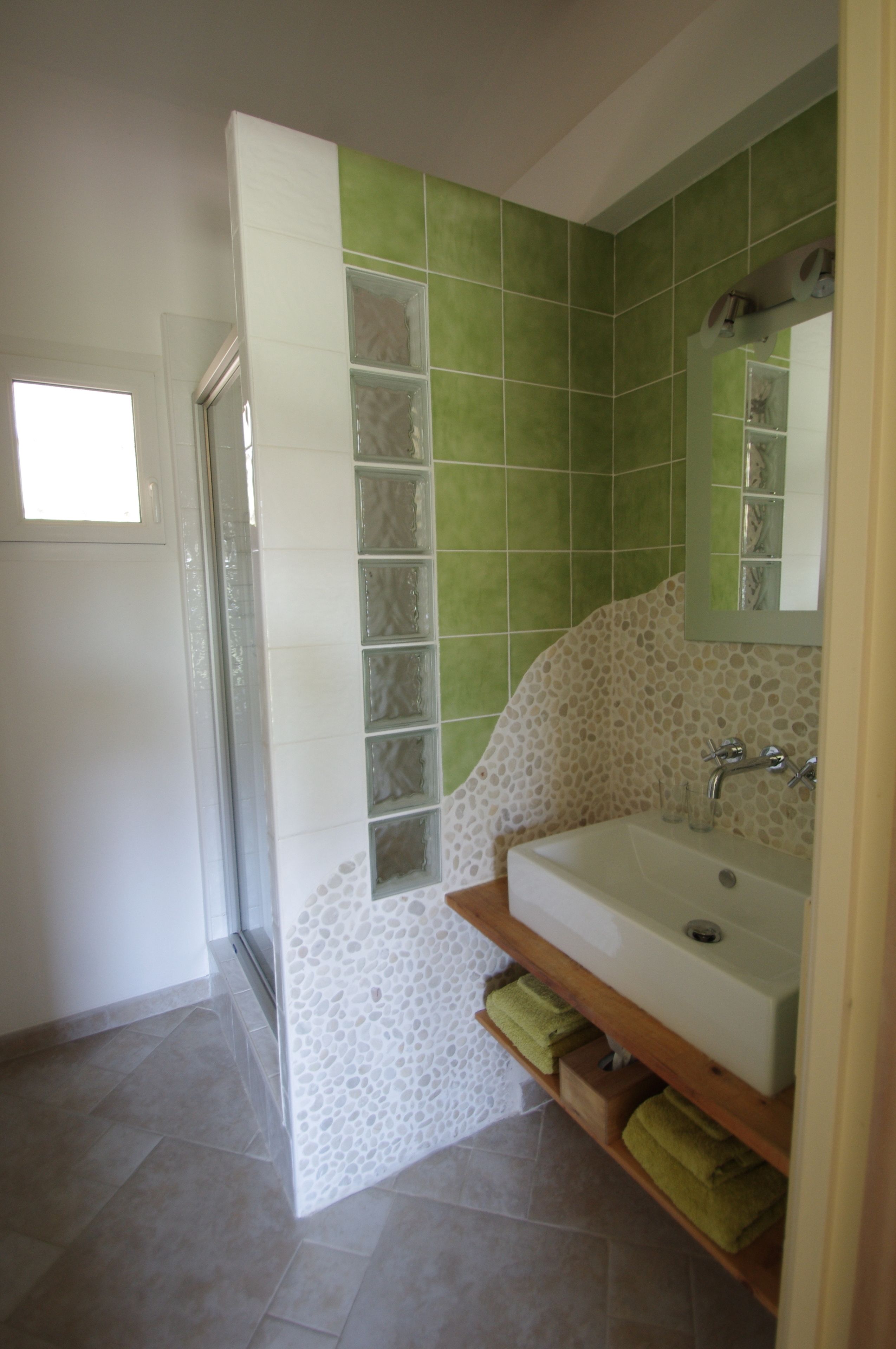 Une salle de bain avec une douche à parois de verre, un lavabo avec un miroir et un sol carrelé.
