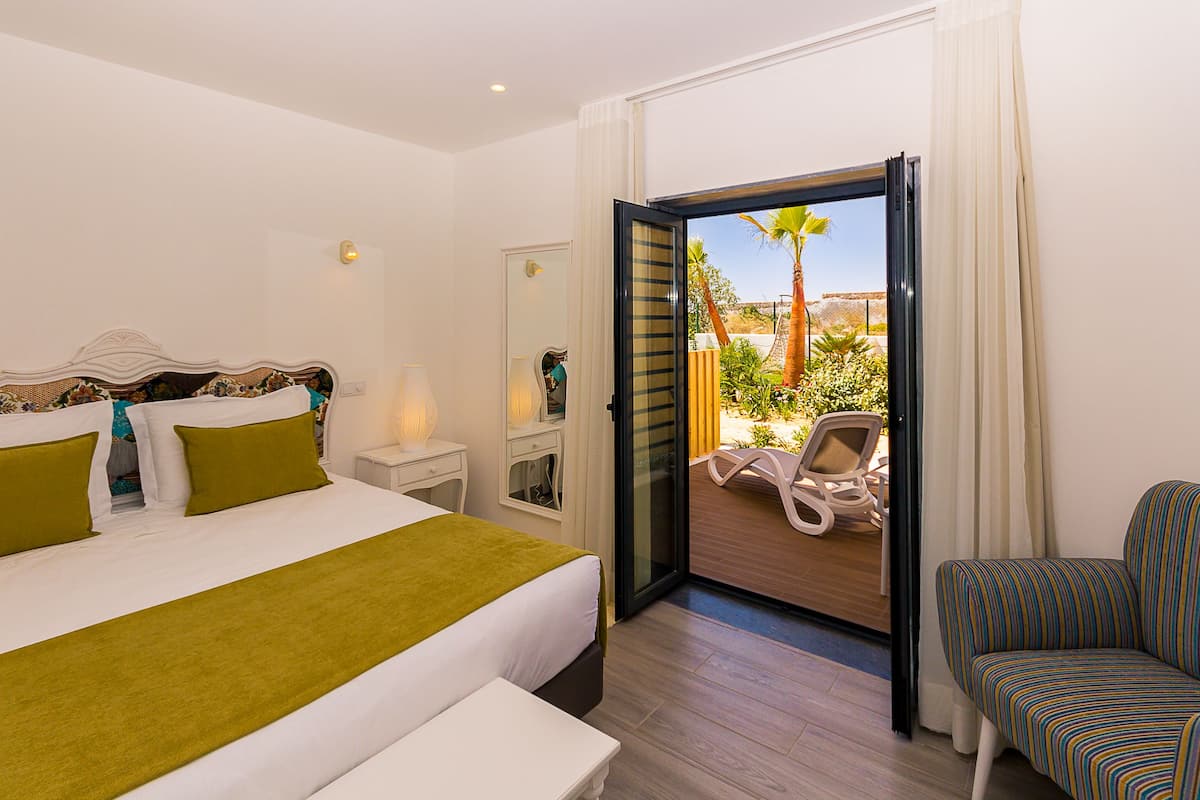 Ein Hotelzimmer mit Bett, Nachttisch, Stuhl und einem Balkon mit Blick ins Freie.