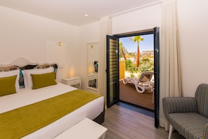 Une chambre d’hôtel comprenant un lit, une table de chevet, une chaise et un balcon avec vue sur l’extérieur.