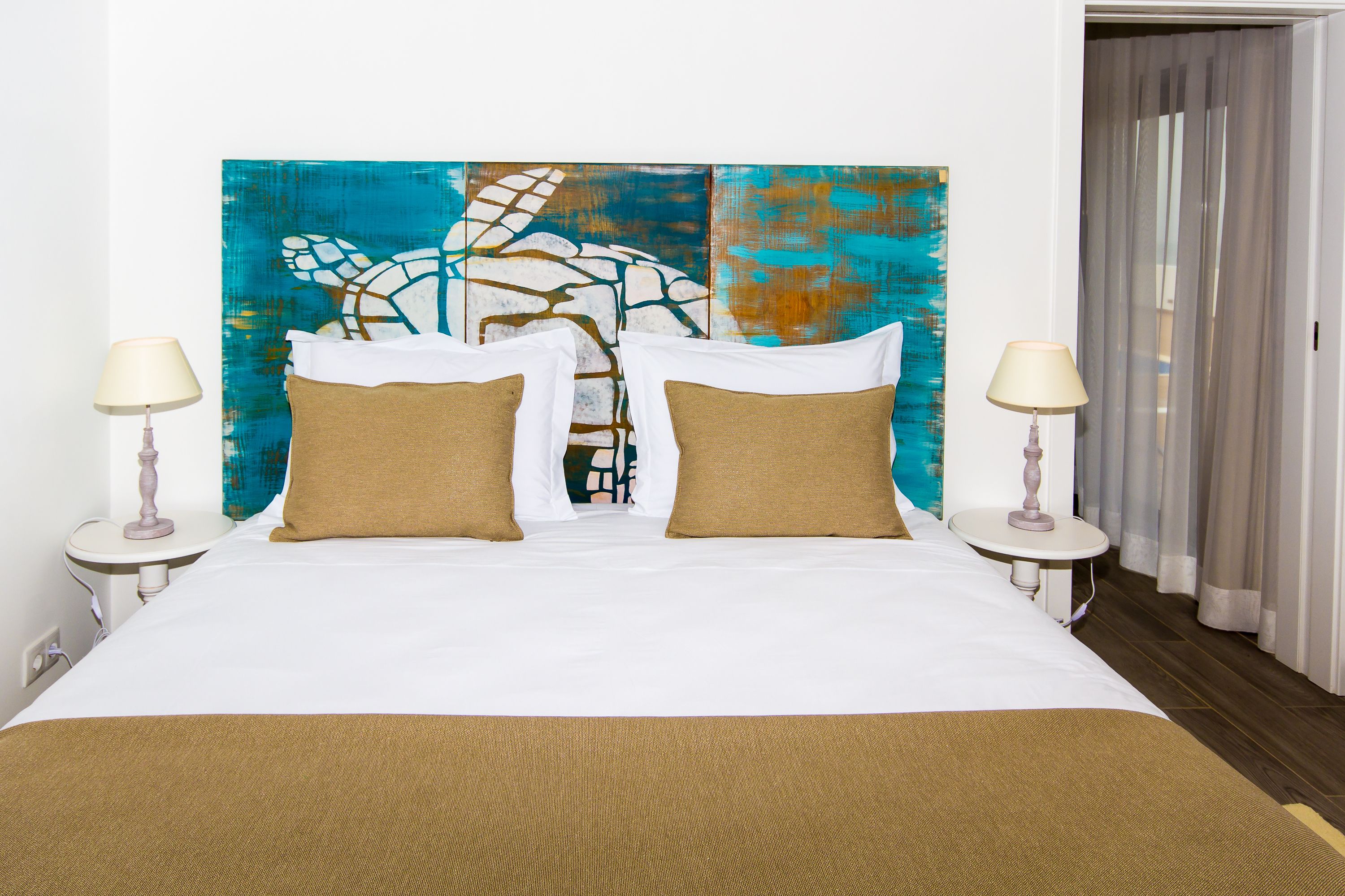 A hotel room with a large bed, two bedside tables, and a colorful abstract painting on the wall.