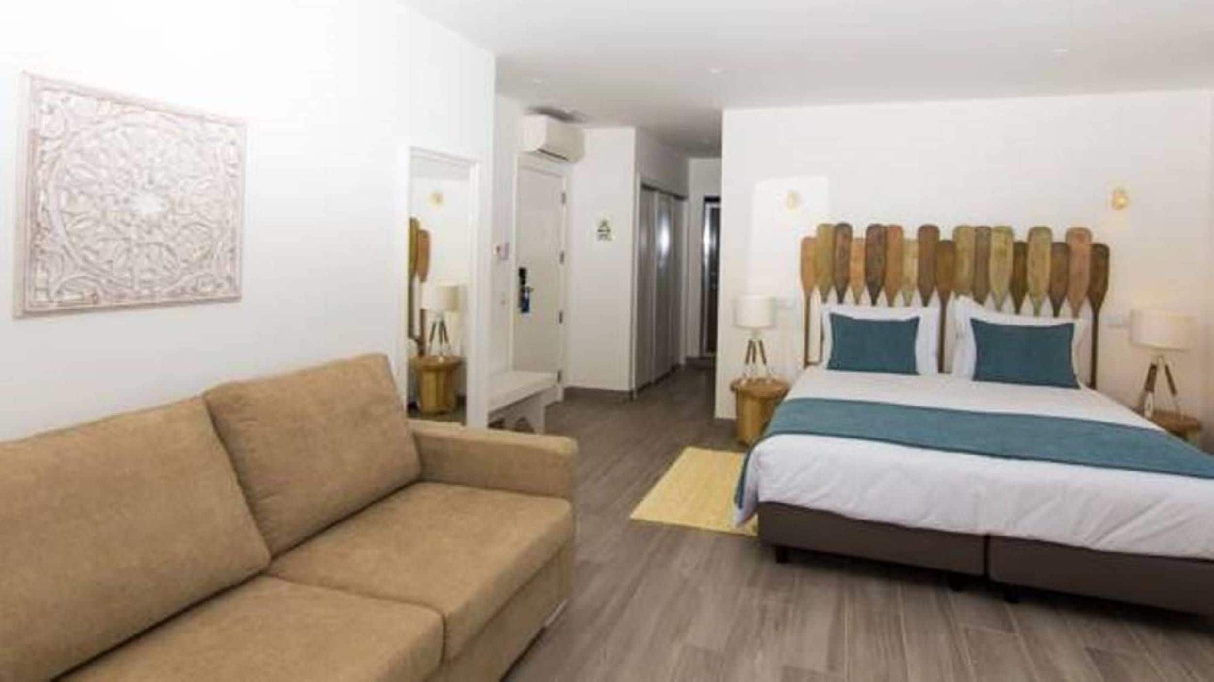 Habitación de hotel con cama, sofá, una mesita y un adorno en la pared.