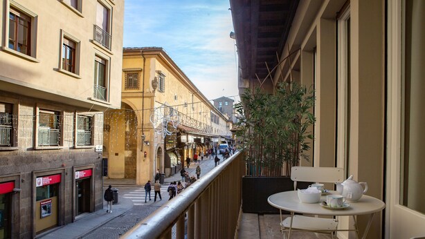 A narrow street with buildings on either side, a balcony with a table and chairs, and a plant. - Le stanze degli amidei (Florence)