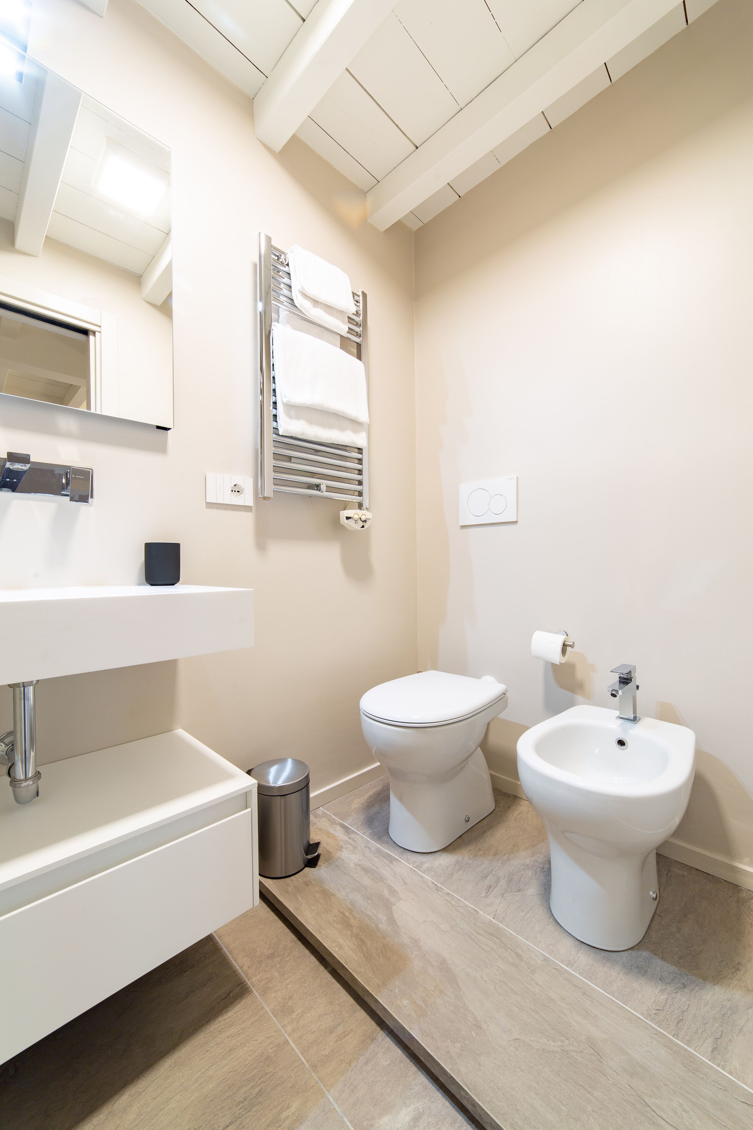 Et moderne badeværelse med en hvid vask, toilet og bidet.