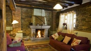 A cozy living room with a stone fireplace, a red sofa, and patterned rugs.