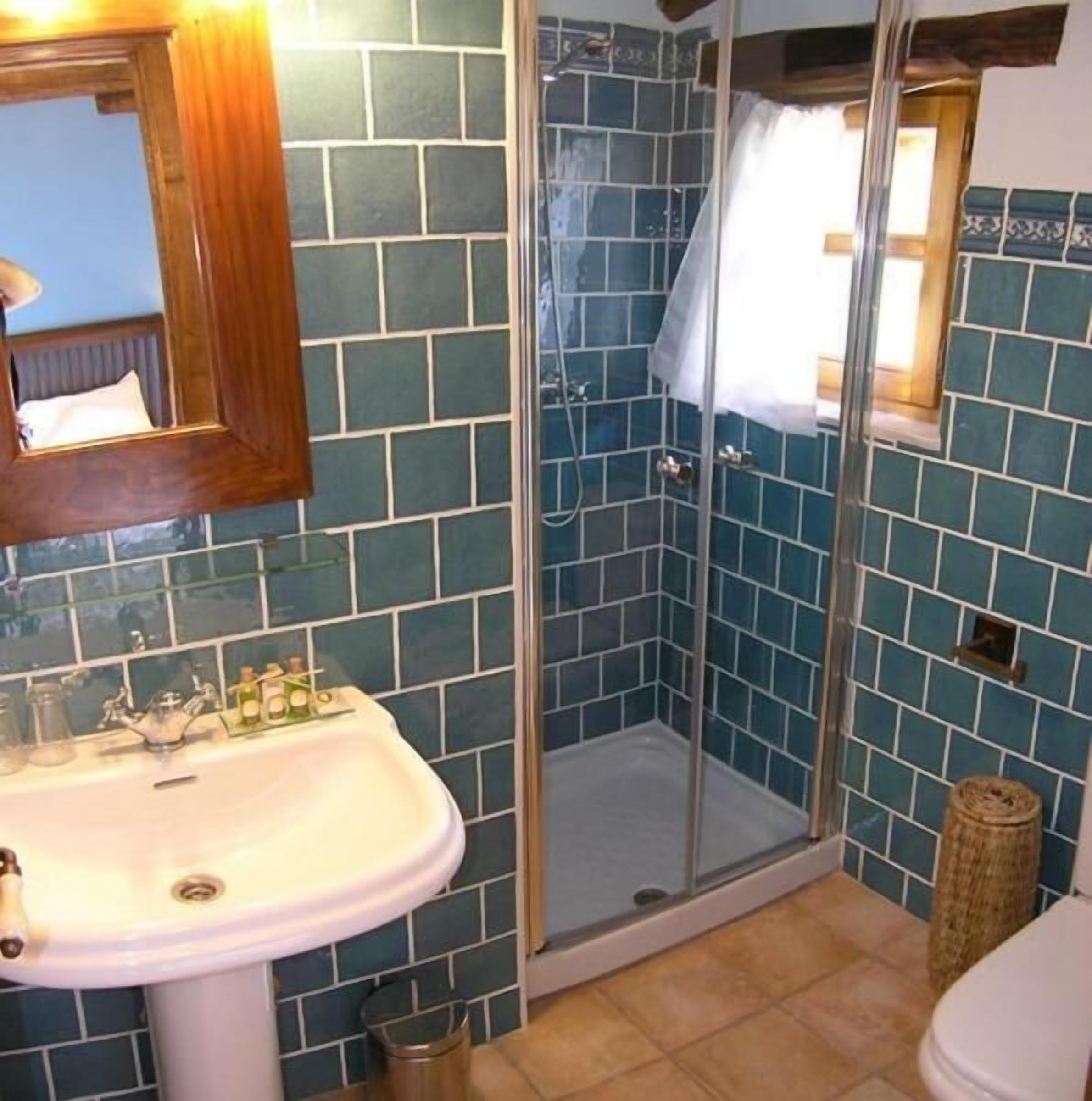 A bathroom with a sink, mirror, and shower area.