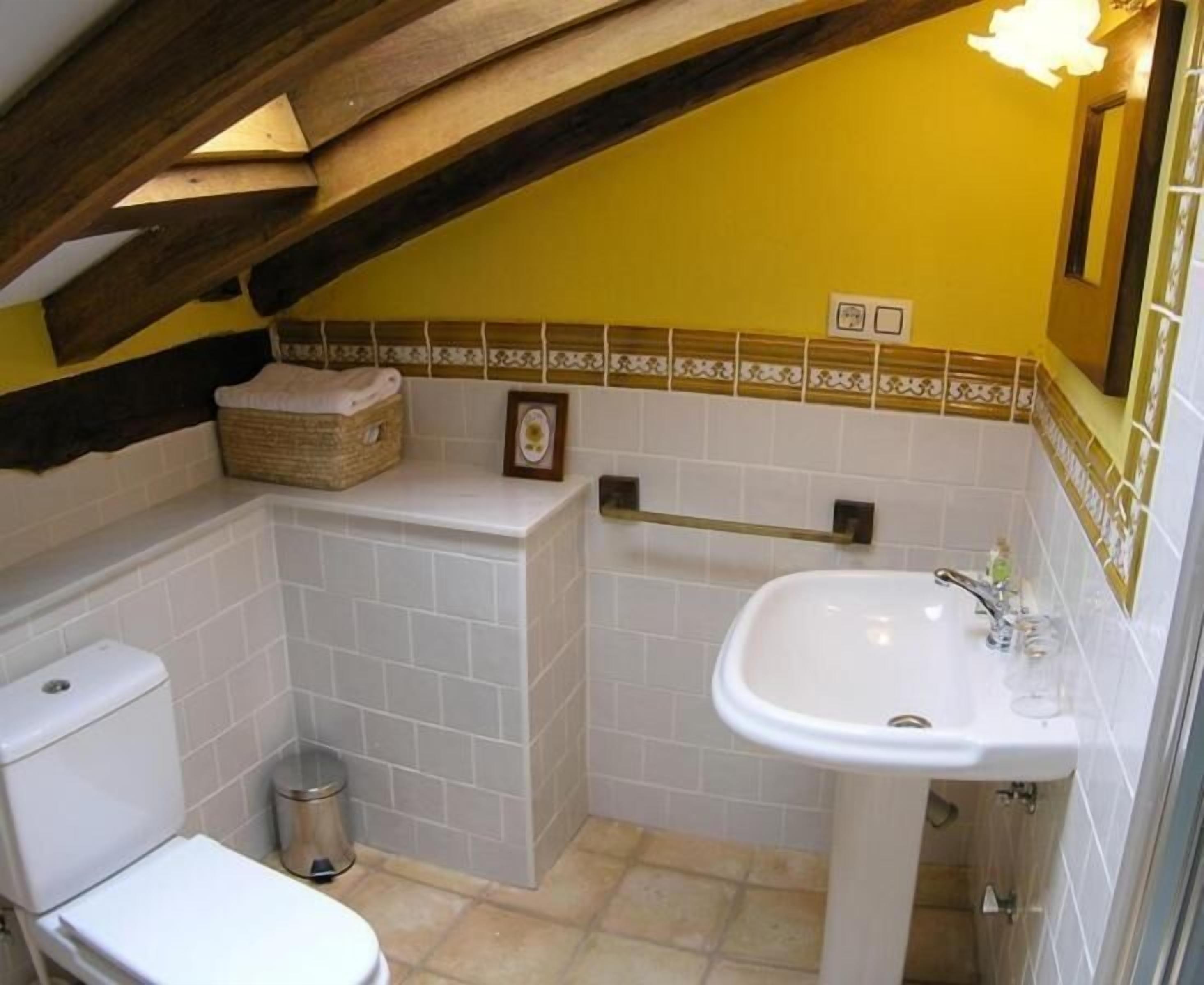 Un baño pequeño con inodoro, lavamanos y zona de ducha.