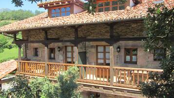 A stone building with a tiled roof, wooden balcony railings, and multiple windows.