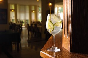 A glass of iced beverage with lime slices on a wooden bar counter in a restaurant. - Világos Hotel Balatonvilágos (Balatonvilagos)