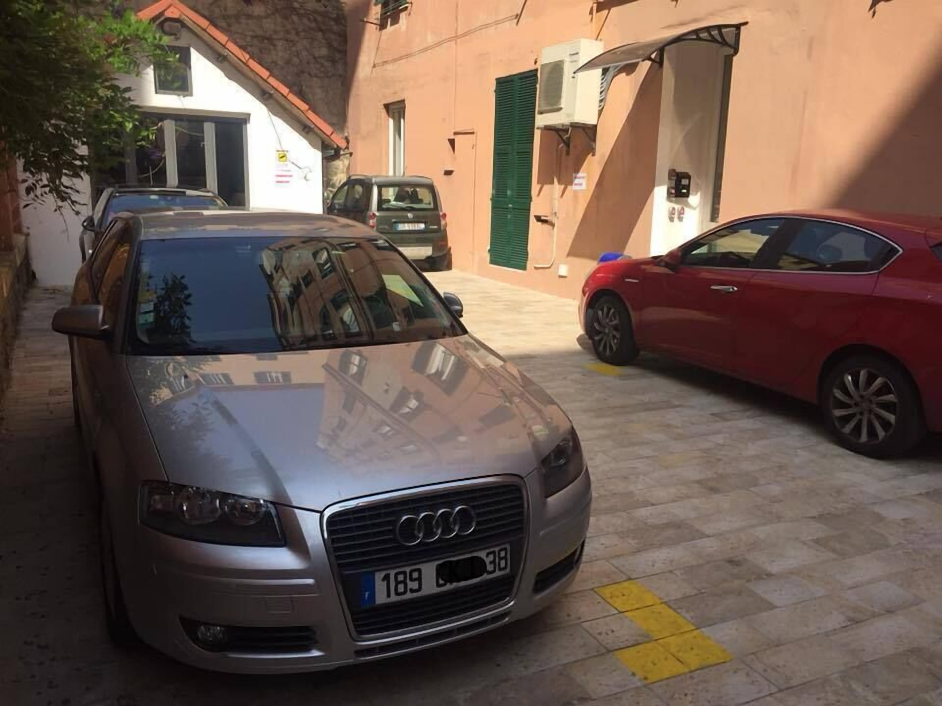 Une Audi argentée était garée dans une rue étroite, bordée de bâtiments des deux côtés.
