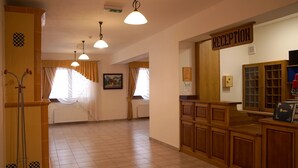 A reception area with a wooden counter, a reception sign, and a window with curtains. - Chata Pieniny (Lesnica)