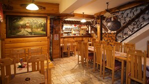 A wooden interior with a bar area, wooden chairs, and a painting on the wall. - Chata Pieniny (Lesnica)