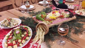 Een feestelijk gedekte tafel met verschillende gerechten, waaronder een schaal met vleeswaren, kazen en groenten, en een glas wijn.
