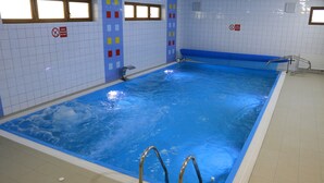 An indoor swimming pool with clear water, tiled walls, and safety railings. - Chata Pieniny (Lesnica)