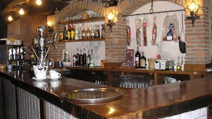 A bar area with a polished counter, shelves with bottles, and hanging items. - Casa Reda - Posada de Viñón (Cillorigo de Liebana)