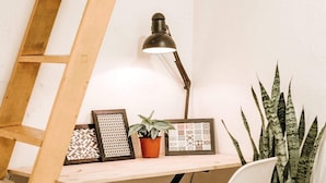 A workspace with a desk, chair, lamp, framed pictures, potted plant, and a wooden ladder. - Michi (Hanoi)
