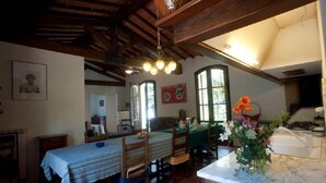 Comedor con una mesa lista para dos personas, sillas de madera y una araña.