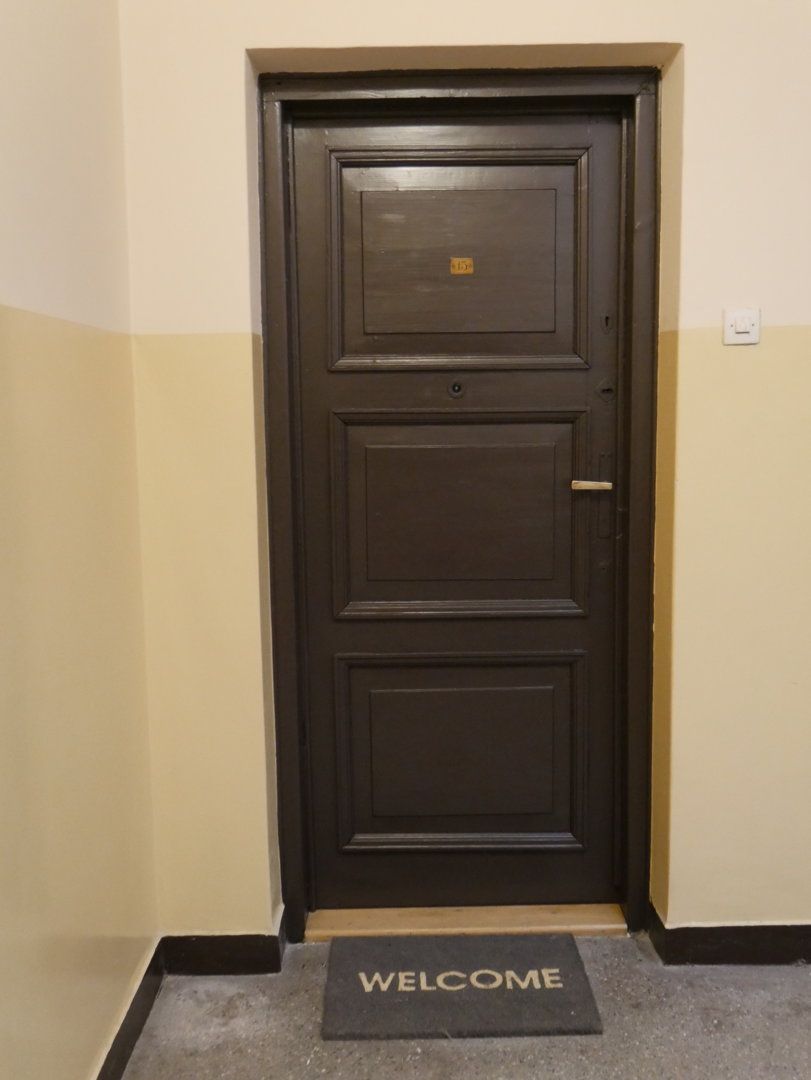 A dark wooden door with a welcome mat at the entrance.