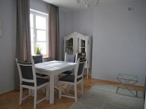 A dining area with a white table and chairs, a glass cabinet, and a chandelier. - AP-Apartments Old Town (Warsaw)