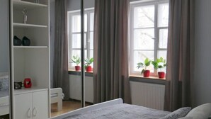 Quarto com cama, guarda-roupa, janela com cortinas e um candelabro.