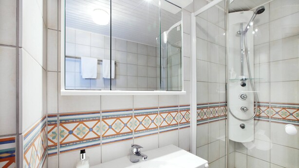 A bathroom with a white sink, a mirror, and a shower. - Hotel Bergschlößchen (Simmern)