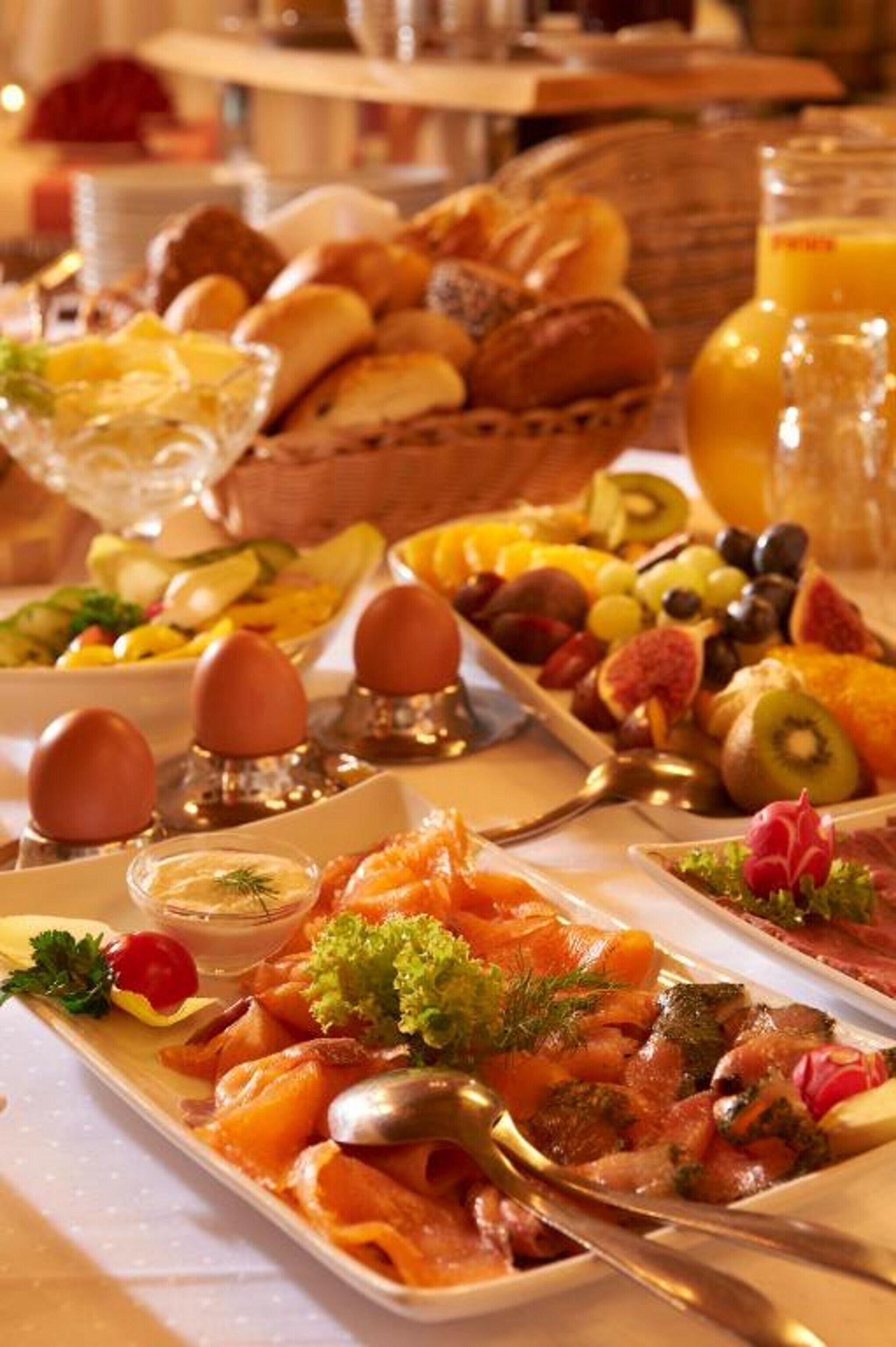 A breakfast buffet with various dishes including fruits, pastries, and seafood.