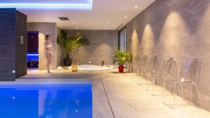 A modern indoor pool area with clear chairs, a hot tub, and potted plants. - Hôtel L'Escale (Escalles)
