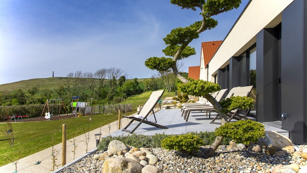A modern house with a patio area, outdoor seating, and a well-maintained garden. - Hôtel L'Escale (Escalles)