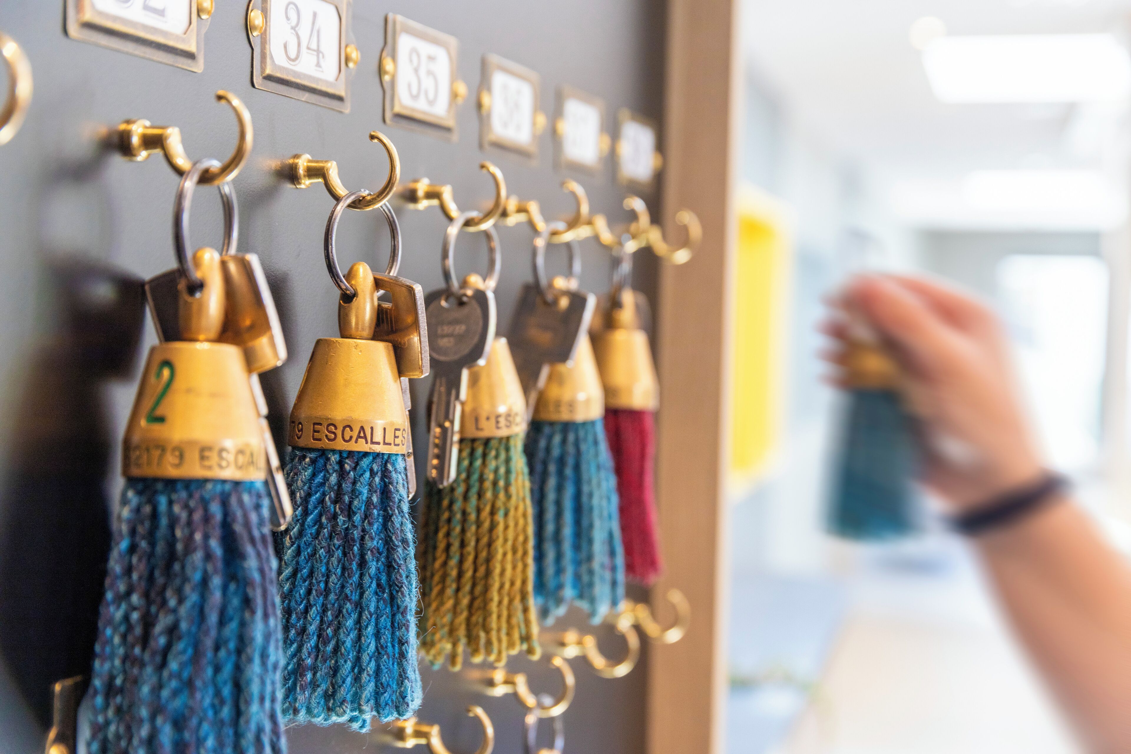 A wall with numbered hooks holding tassels, and a hand reaching for a tassel.