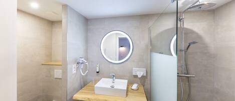 A modern bathroom with a toilet, a sink with a mirror, and a shower.