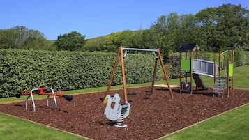 A playground with swings, a slide, and a climbing structure.