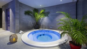 A modern spa area with a hot tub, a spherical wooden sculpture, and potted plants. - Hôtel L'Escale (Escalles)