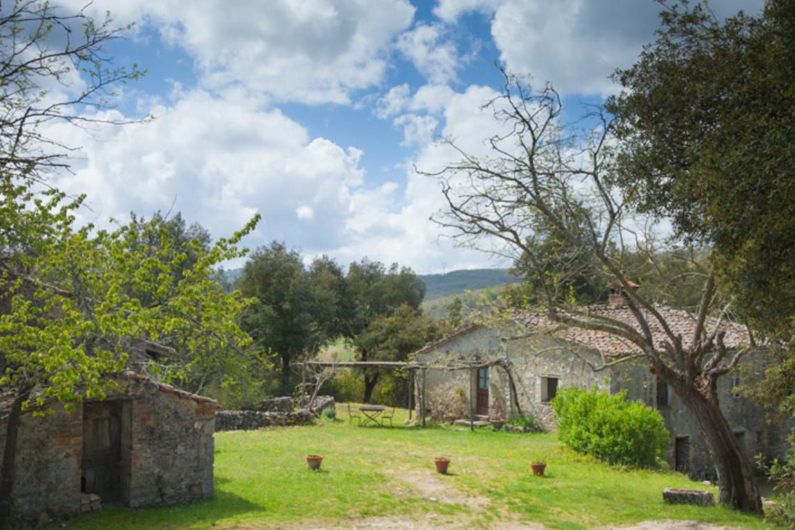 Un edificio de piedra rústico con un jardín delantero, rodeado de árboles y un cielo despejado.