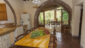 Una cocina rústica con una mesa y sillas de madera, un refrigerador y una ventana con vista a un jardín.