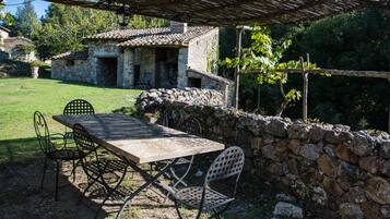 An outdoor dining area with a stone wall, a table, and metal chairs.