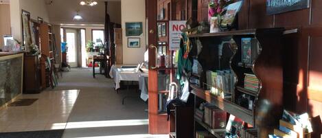 A hotel lobby with a reception desk, a waiting area, and a bookshelf filled with books and magazines.