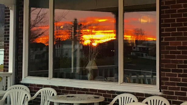 Ein Fenster mit Blick auf einen Sonnenuntergang über einer Wohngegend.