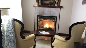 Ein gemütliches Wohnzimmer mit Kamin, zwei Sesseln, einem Couchtisch und einem Teppich.