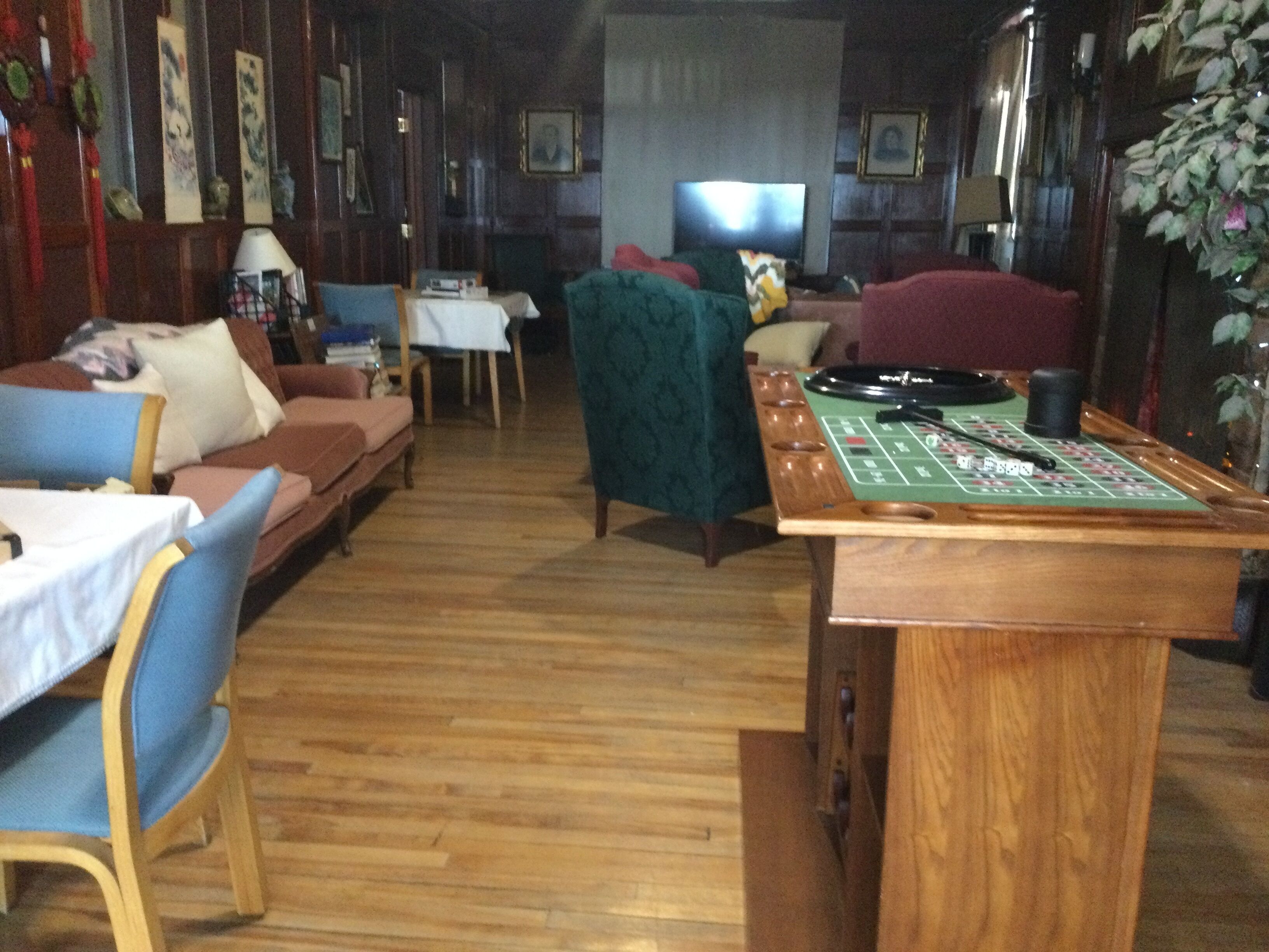 Una sala de estar acogedora con un sillón verde, una mesa de centro de madera con tapa de fieltro verde y un televisor al fondo.