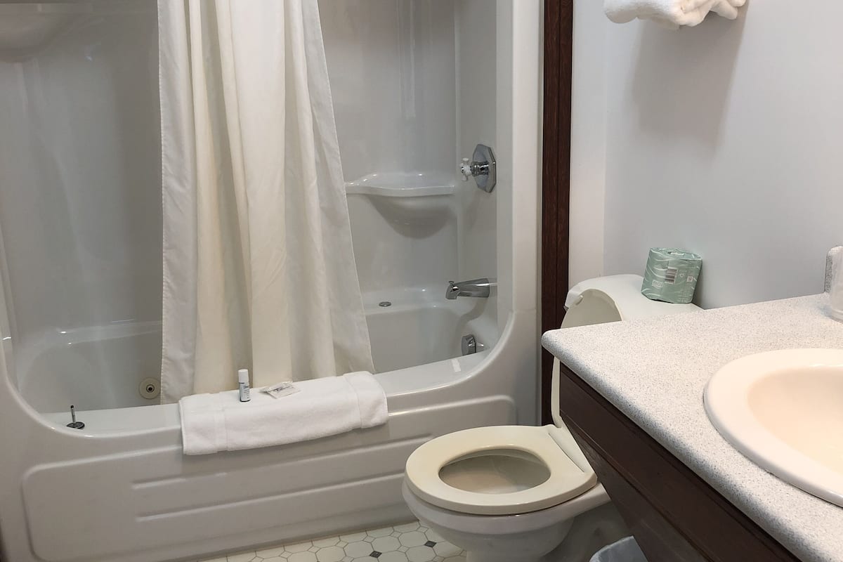 deluxe, 2 queens, fireplace | bathroom | combined shower/bathtub, deep-soaking bathtub, rainfall showerhead